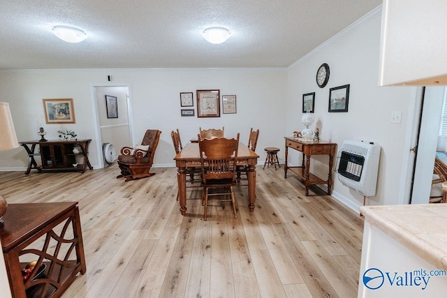 dining area with heating unit, a textured ceiling, crown molding, and light wood-style flooring