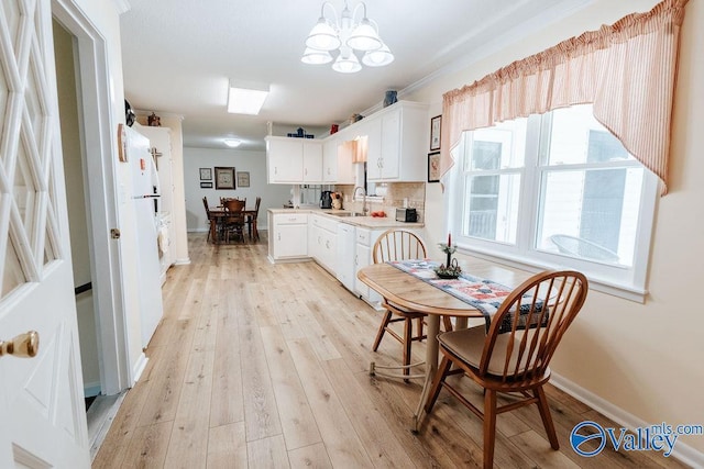 dining area featuring light wood-style floors, baseboards, and an inviting chandelier