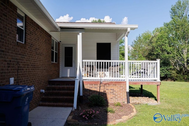 entrance to property with a yard, brick siding, and covered porch