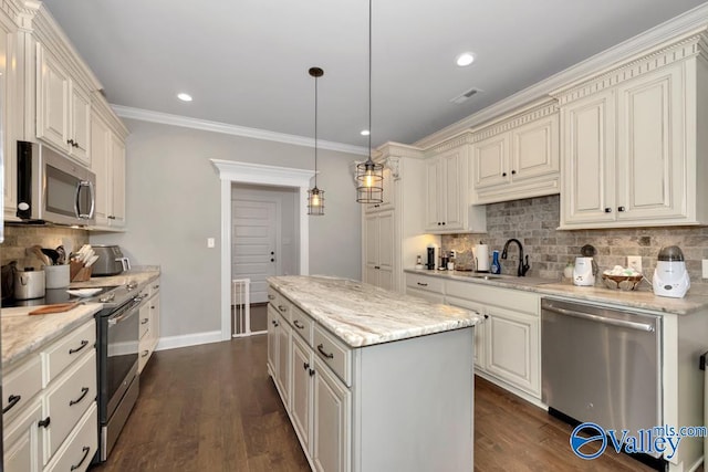 kitchen with dark wood-type flooring, sink, appliances with stainless steel finishes, decorative light fixtures, and a kitchen island