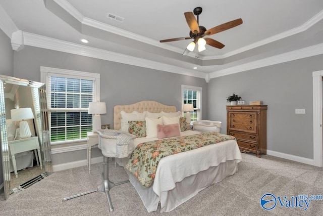 bedroom with a raised ceiling, multiple windows, ornamental molding, and ceiling fan