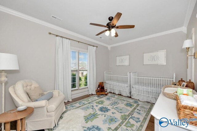 bedroom with ceiling fan, ornamental molding, a crib, and hardwood / wood-style flooring