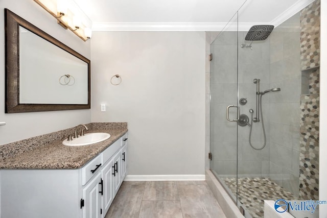 full bathroom with baseboards, vanity, a shower stall, and crown molding