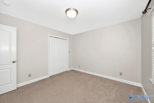 unfurnished bedroom featuring a closet, baseboards, and carpet flooring