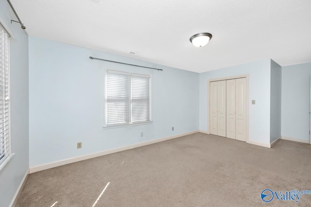 unfurnished bedroom featuring a closet, carpet flooring, a textured ceiling, and baseboards