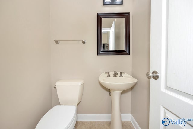 bathroom with tile patterned flooring, toilet, baseboards, and a sink