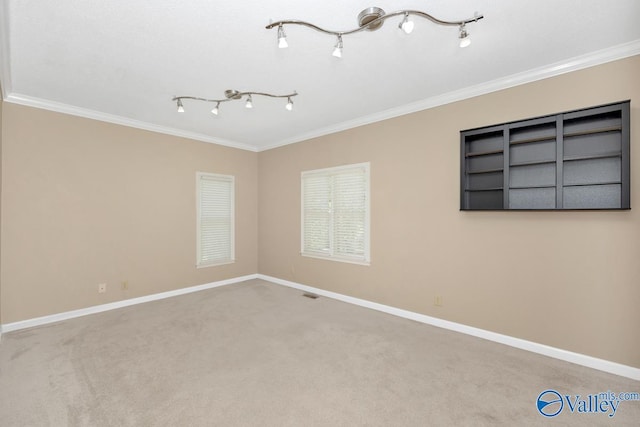 carpeted empty room featuring baseboards, ornamental molding, and rail lighting