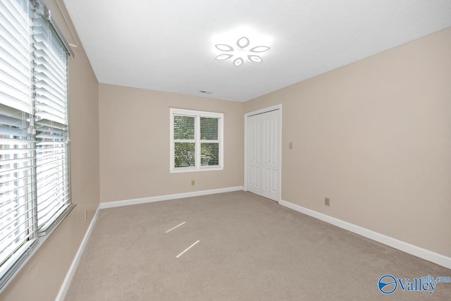 empty room featuring light colored carpet and baseboards