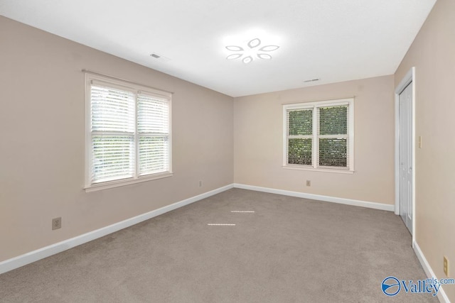 empty room with visible vents, baseboards, and carpet flooring