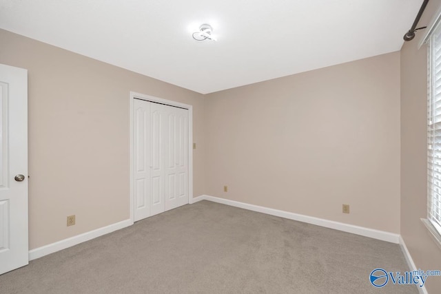 unfurnished bedroom featuring carpet, baseboards, and a closet