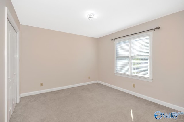 unfurnished bedroom with light colored carpet, baseboards, and a closet