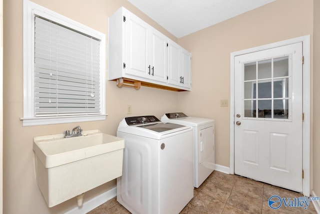 laundry area featuring light tile patterned floors, baseboards, cabinet space, a sink, and washer and clothes dryer