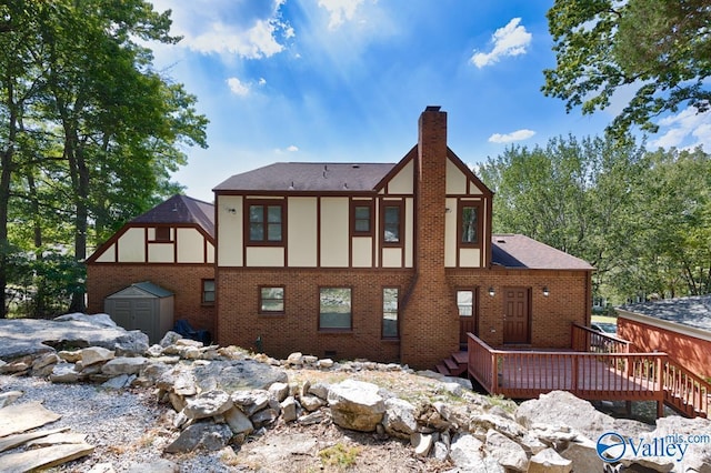 back of house featuring brick siding, a chimney, a storage shed, and an outbuilding