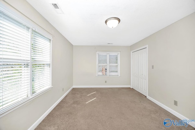 carpeted spare room featuring visible vents and baseboards