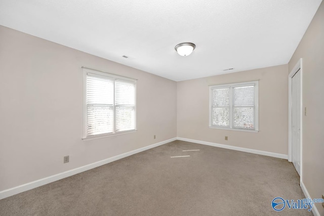 unfurnished room with baseboards and carpet