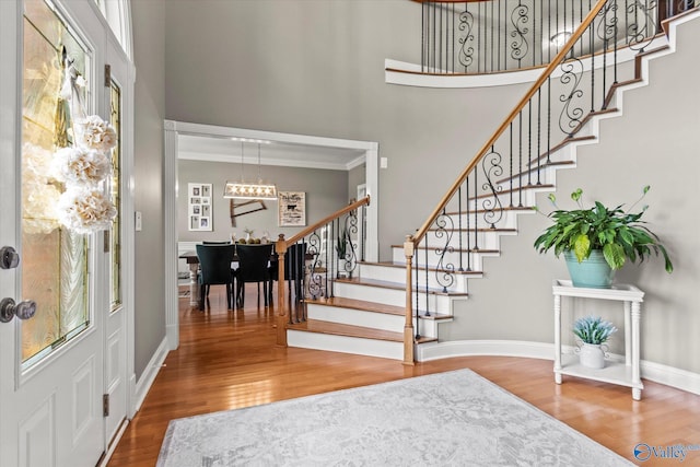 foyer entrance with hardwood / wood-style flooring, ornamental molding, and a towering ceiling