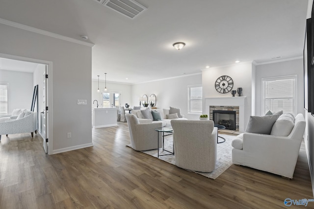 living room featuring baseboards, visible vents, wood finished floors, and a stone fireplace