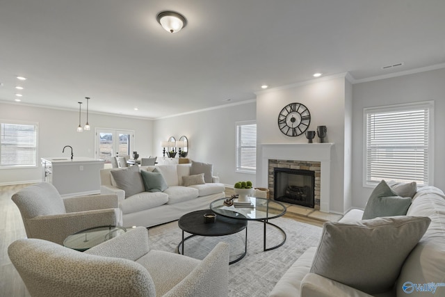 living room featuring light wood-type flooring, baseboards, visible vents, and crown molding