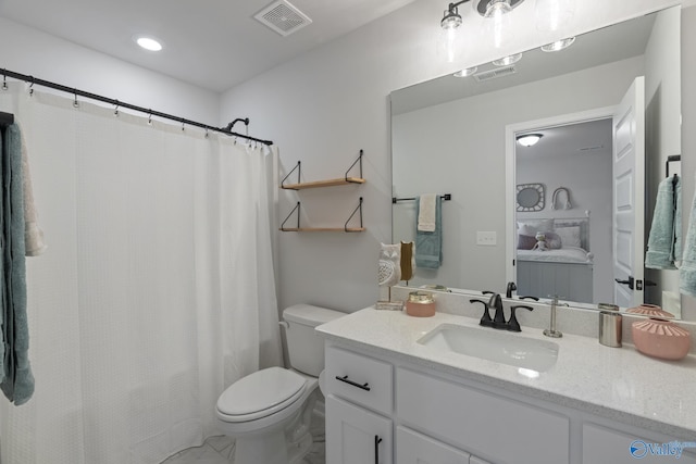 bathroom with toilet, vanity, and visible vents