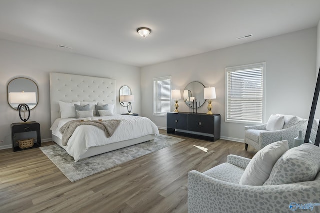 bedroom featuring baseboards, visible vents, and wood finished floors