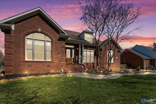 view of front of property with brick siding, crawl space, and a front yard