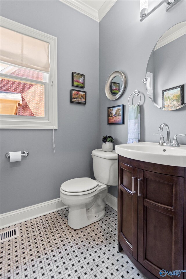 half bathroom with toilet, vanity, baseboards, and ornamental molding