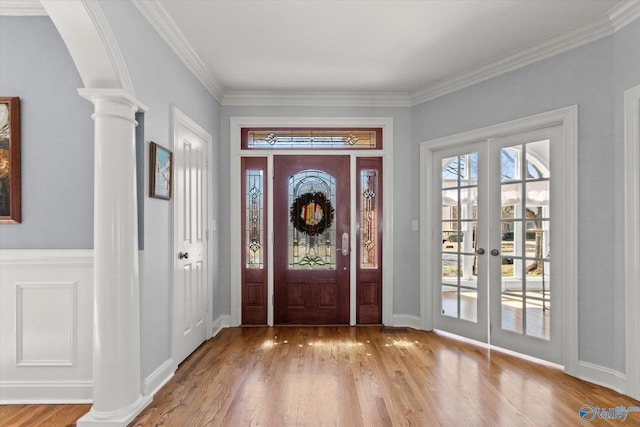 entryway with crown molding, french doors, wood finished floors, arched walkways, and ornate columns