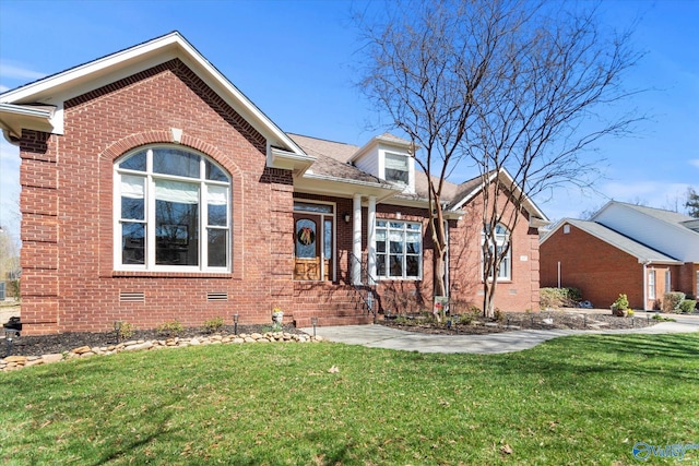 view of front of house with a shingled roof, a front yard, brick siding, and crawl space