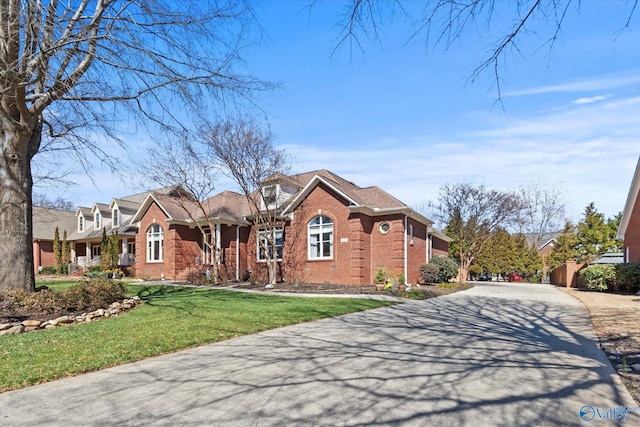 view of front of home with a front yard, brick siding, and driveway