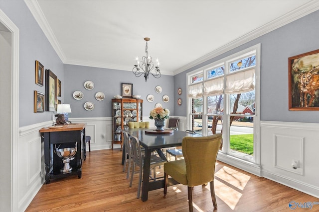 dining room with a wainscoted wall, an inviting chandelier, and light wood finished floors