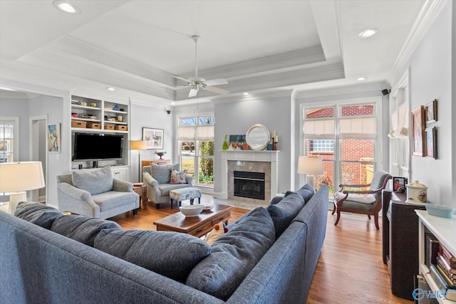 living area featuring recessed lighting, a tray ceiling, wood finished floors, and a tiled fireplace