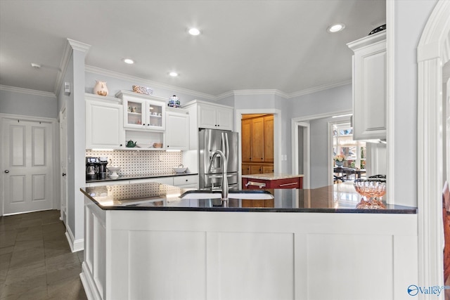 kitchen with a sink, stainless steel fridge, white cabinetry, tasteful backsplash, and a center island