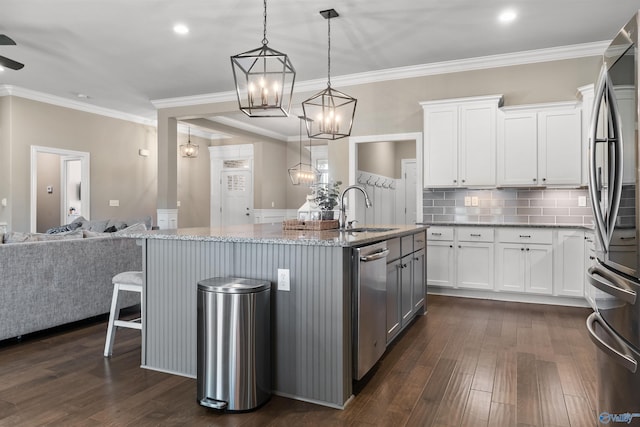 kitchen with light stone countertops, open floor plan, an island with sink, freestanding refrigerator, and a sink