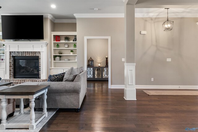 living room with built in shelves, baseboards, dark wood-style flooring, crown molding, and a brick fireplace