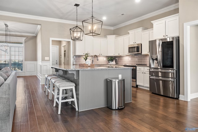 kitchen featuring dark wood finished floors, white cabinets, appliances with stainless steel finishes, and light stone counters