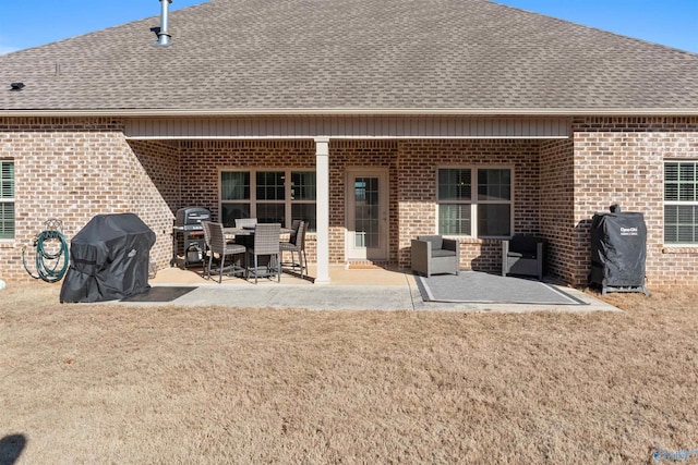 rear view of property with a patio area, brick siding, roof with shingles, and a lawn