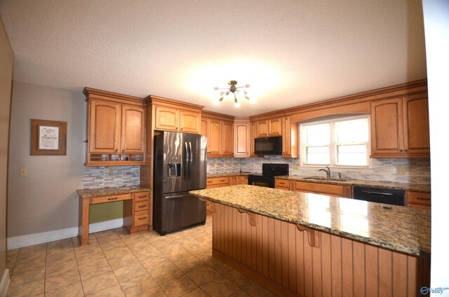 kitchen featuring sink, a chandelier, a kitchen breakfast bar, black appliances, and light stone countertops