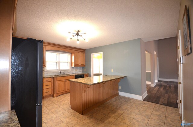 kitchen with sink, a kitchen bar, decorative backsplash, light stone counters, and black appliances