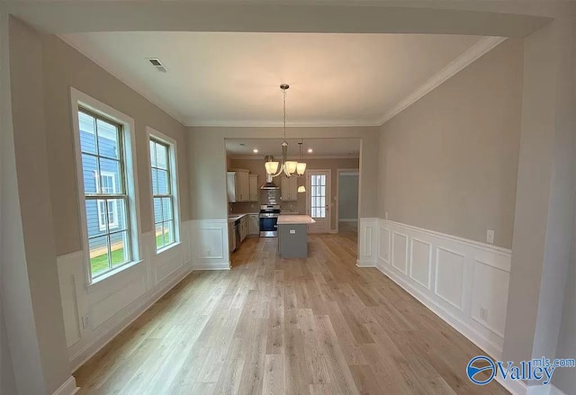 unfurnished dining area with a chandelier, crown molding, and light hardwood / wood-style floors