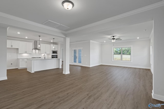 unfurnished living room with crown molding, sink, ceiling fan, and dark wood-type flooring