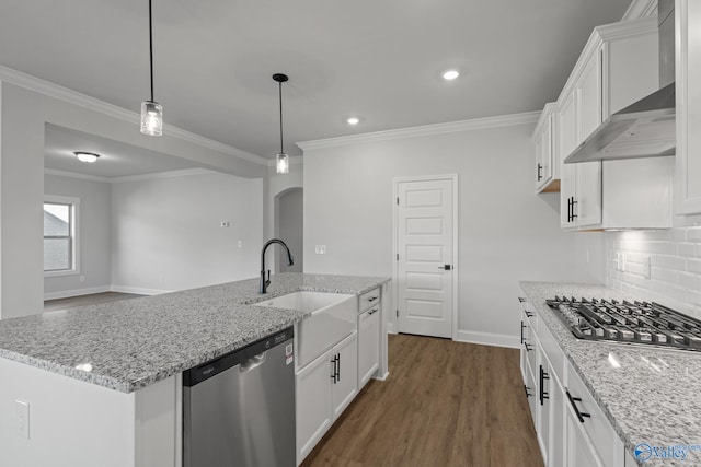 kitchen featuring light stone counters, wall chimney exhaust hood, stainless steel appliances, a center island with sink, and white cabinets