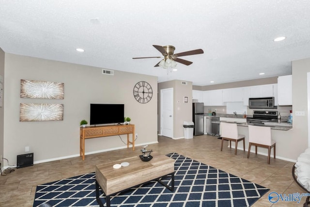 living room featuring ceiling fan and a textured ceiling