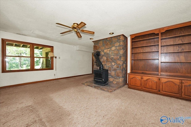 143 Maze Dr, Hartselle, AL 35640 - unfurnished living room featuring a wood stove, a textured ceiling, ceiling fan, light carpet, and baseboards