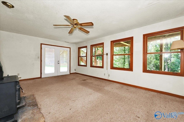 143 Maze Dr, Hartselle, AL 35640 - unfurnished living room featuring a wood stove, french doors, baseboards, ceiling fan, and a textured ceiling