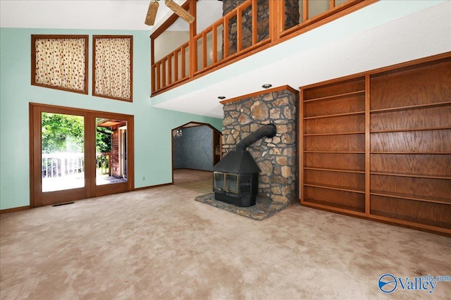 143 Maze Dr, Hartselle, AL 35640 - unfurnished living room with a high ceiling, a wood stove, carpet, baseboards, and a ceiling fan