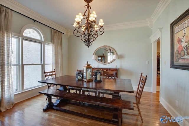 dining area with an inviting chandelier, crown molding, wood finished floors, and baseboards