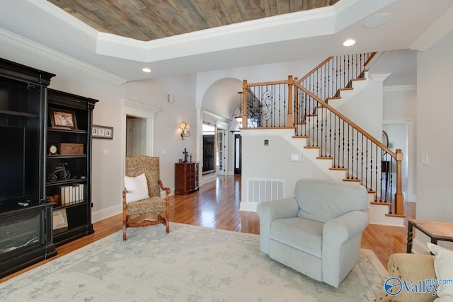 living room featuring arched walkways, visible vents, crown molding, and wood finished floors