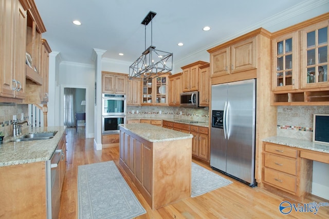 kitchen with a center island, light wood-type flooring, light stone counters, appliances with stainless steel finishes, and a sink