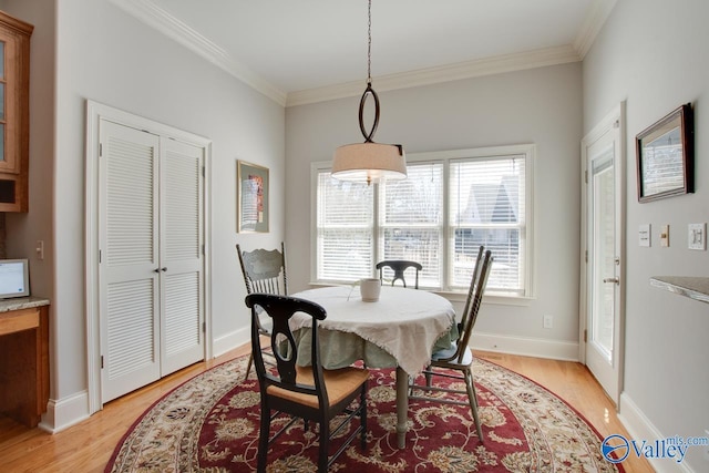 dining space featuring baseboards, light wood-style flooring, and crown molding