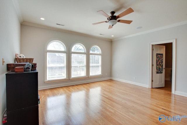 interior space featuring visible vents, light wood-style flooring, baseboards, and ornamental molding